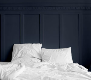 White bed linen on a mattress in a midnight blue bedroom